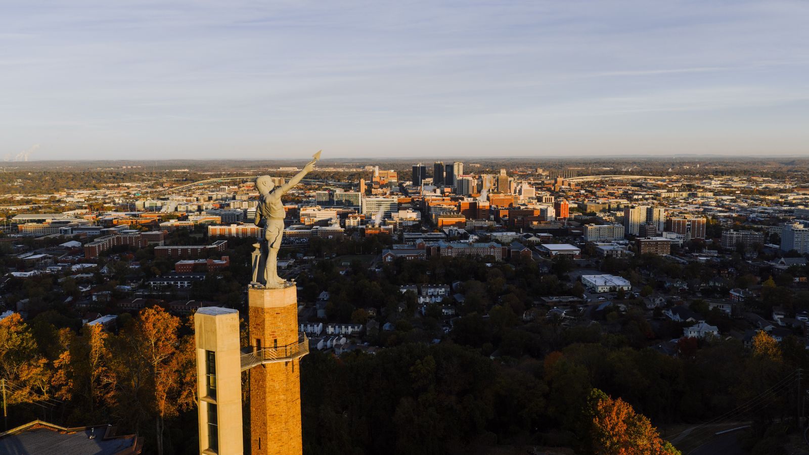 The Vulcan statue on its tower at Vulcan Park, looking over the Birmingham skyline at sunset, one of the top things to do in Alabama