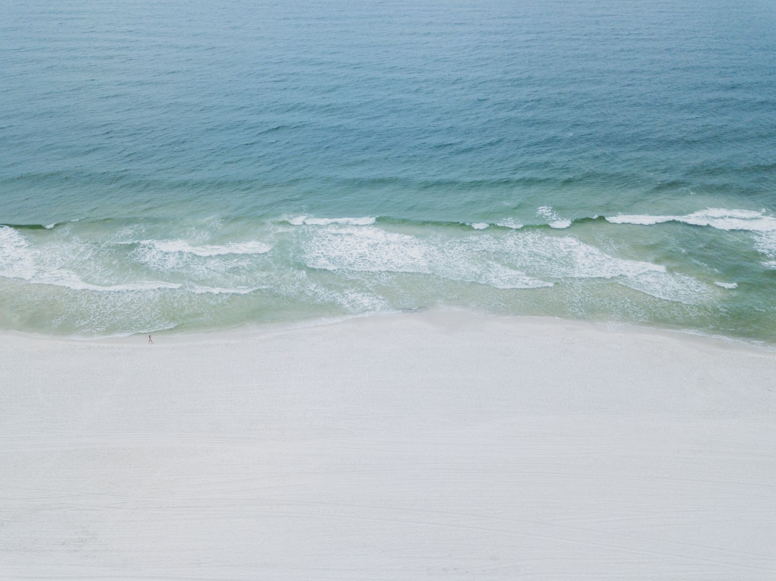 Aerial view of white sand and green Gulf water at Orange Beach, one of the best places to visit in Alabama